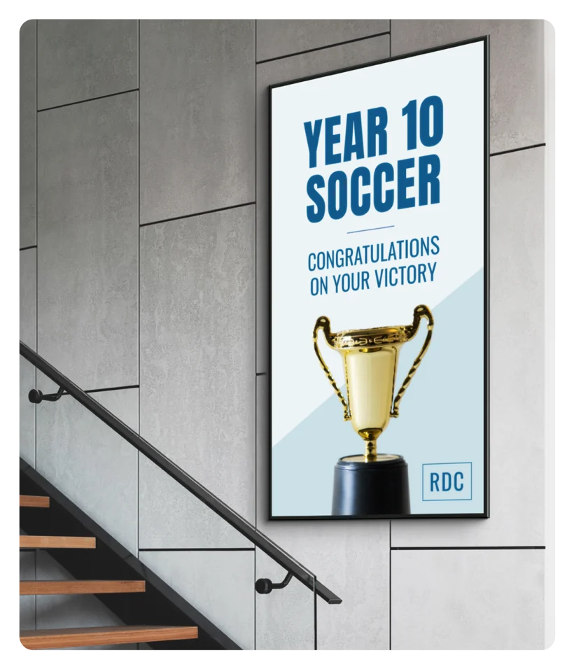 Freestanding indoor digital signage display in a school corridor showing student achievements