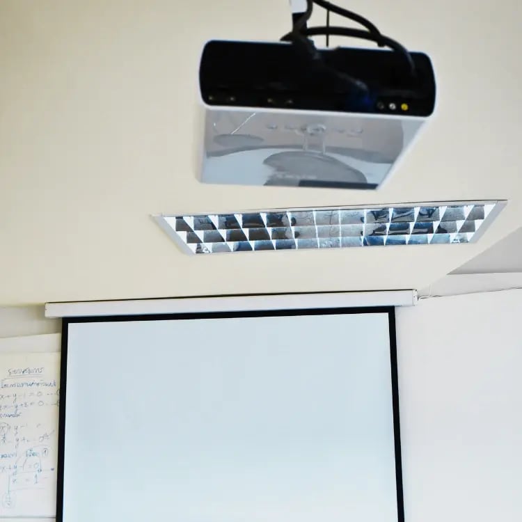 Ceiling-mounted classroom projector with pull-down screen, ready for use in a school learning space Ceiling-mounted classroom projector with pull-down screen, ready for use in a school learning space