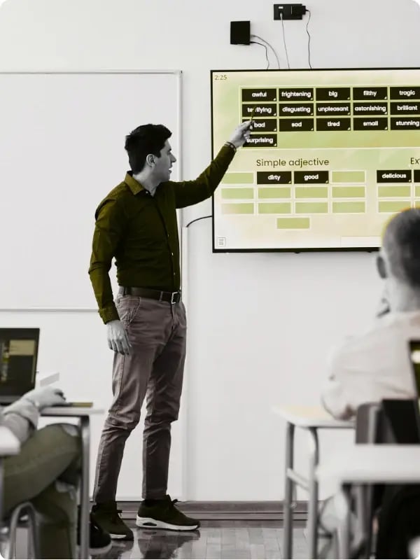 Teacher leading a classroom lesson using a wall-mounted interactive display, demonstrating effective use of AV technology for education.